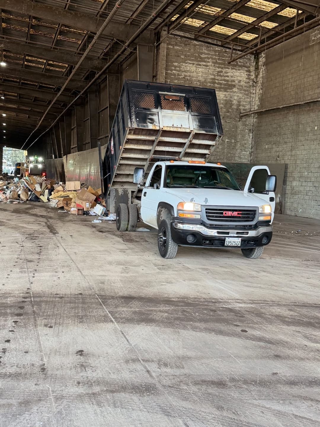 Commercial junk removal truck unloading debris inside an industrial facility